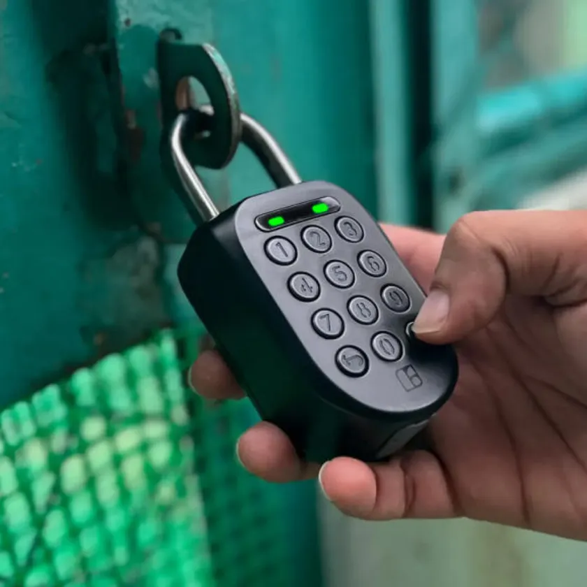Eine Hand hält ein smartes Vorhängeschloss mit Nummernpad